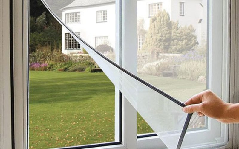 Velcro mosquito net being pressed onto a white window frame